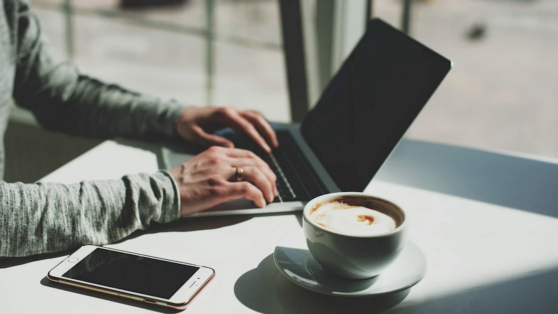 person working on Laptop with coffee and phone