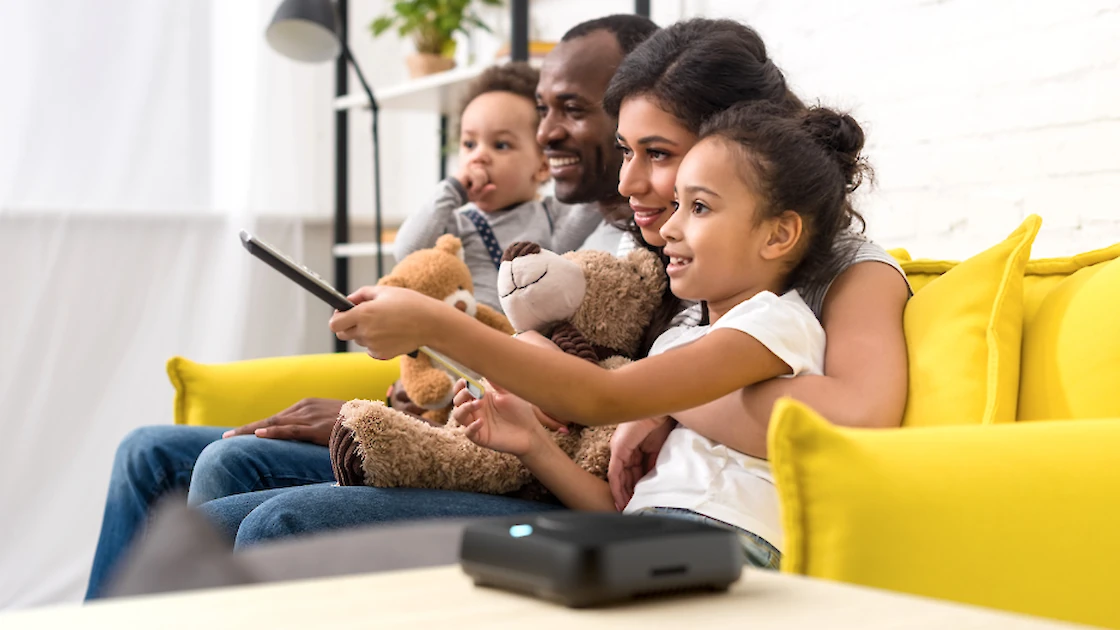 family enjoying some entertainment on the couch, mom, dad and kids.