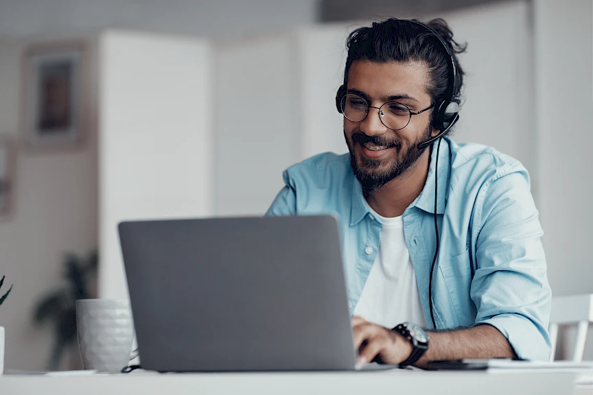 A man at his computer talking on the phone.