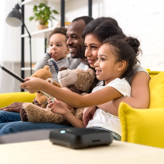 A family watching TV with an Amber X device in the foreground.